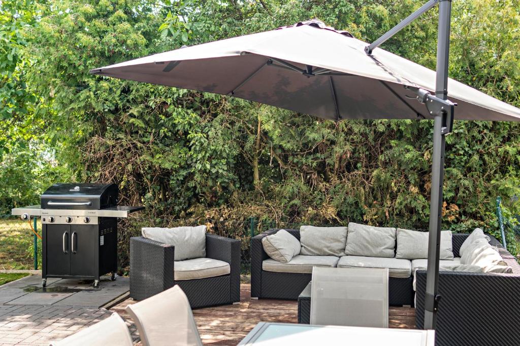 a patio with an umbrella and chairs and a grill at Geräumiges Haus mit Garten Terasse in Nuremberg