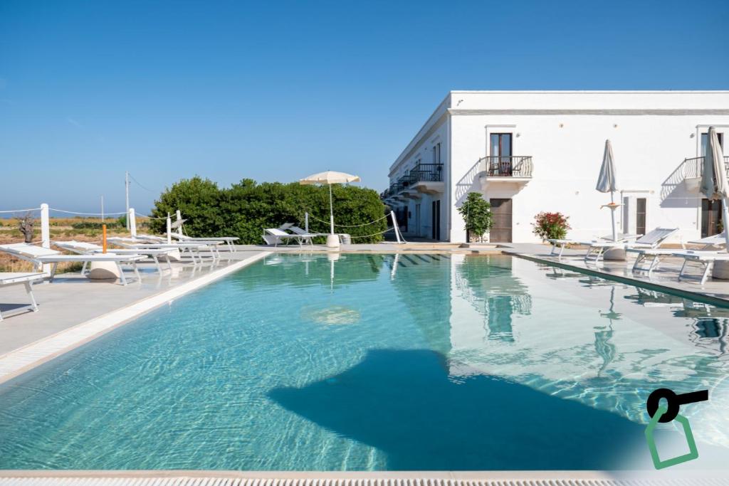 a large swimming pool with chairs and a building at Hotiday Fasano Mare in Savelletri di Fasano