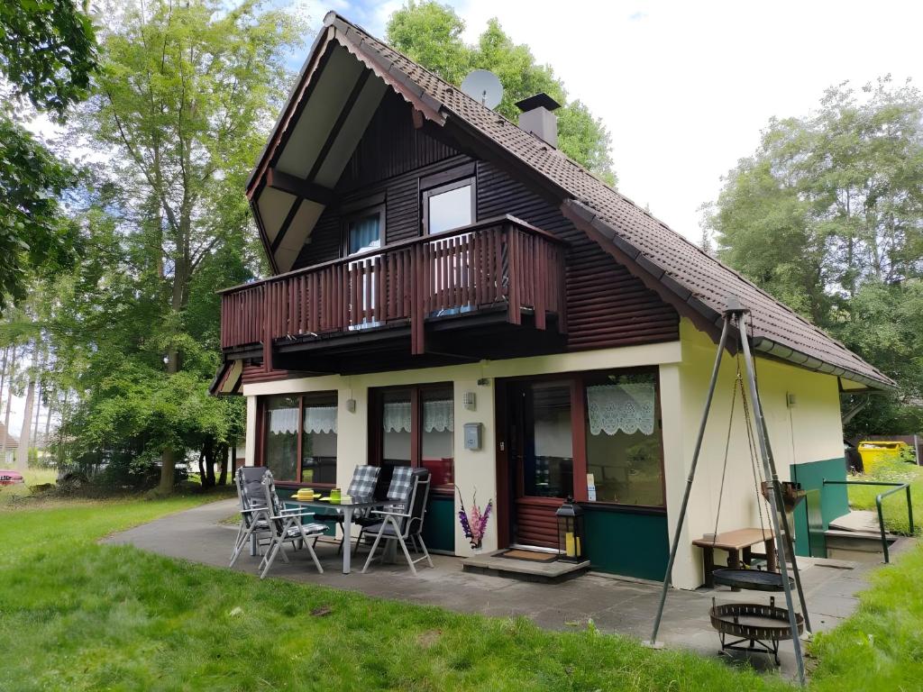 a house with a balcony and a table and chairs at Ferienhaus Tindy am Silbersee in Frielendorf