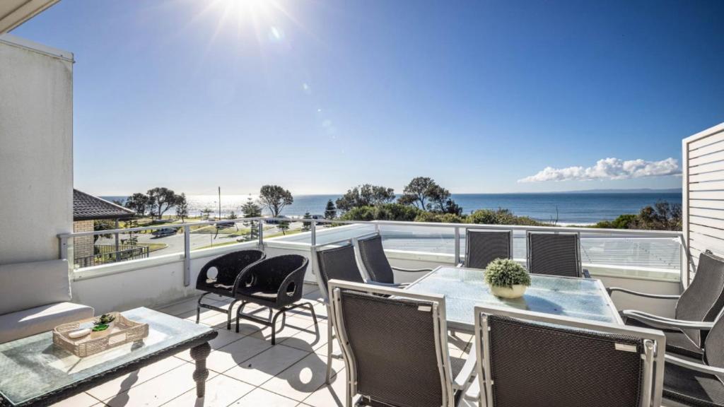 a balcony with a table and chairs and the ocean at The Lookout in Woorim