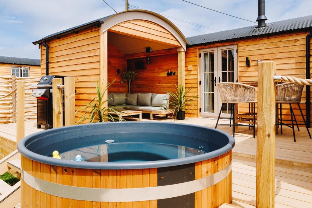 a hot tub on a deck next to a house at Nestledstays – The Meadow in Binsted