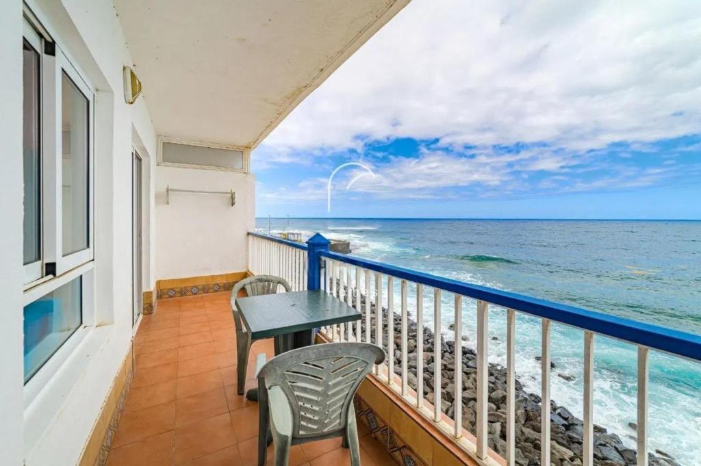 a balcony with a table and chairs and the ocean at oceano de bajamar in Bajamar