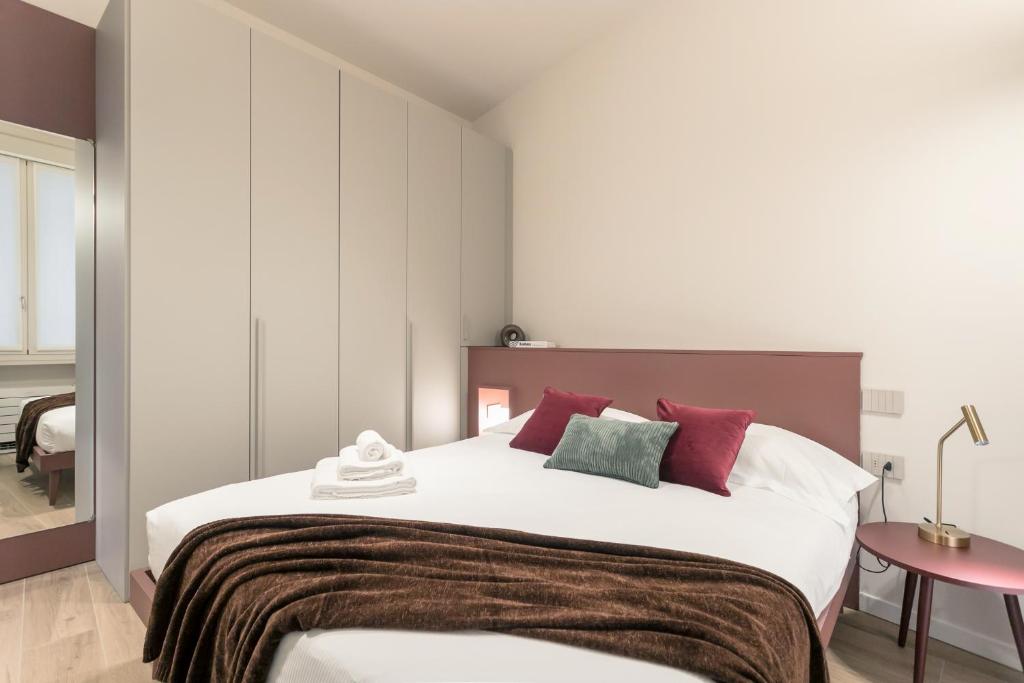 a bedroom with a large bed with red and green pillows at GuestHost - Vivaldi Autunno Apartment in Treviglio