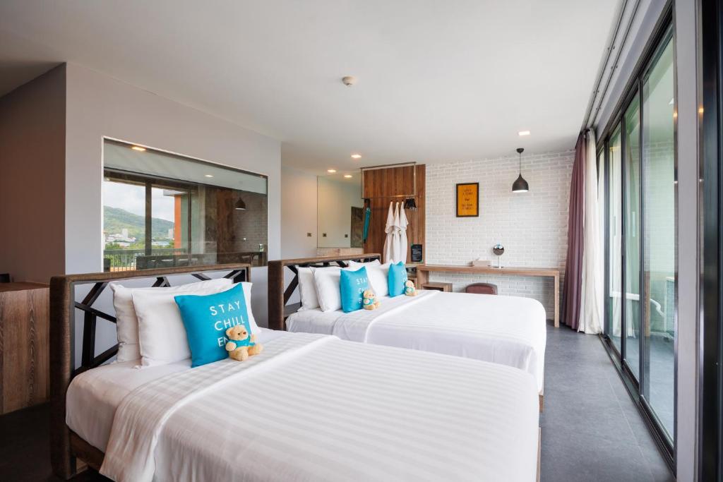 A bright twin room with two beds, full-height windows, and a compact dressing area.