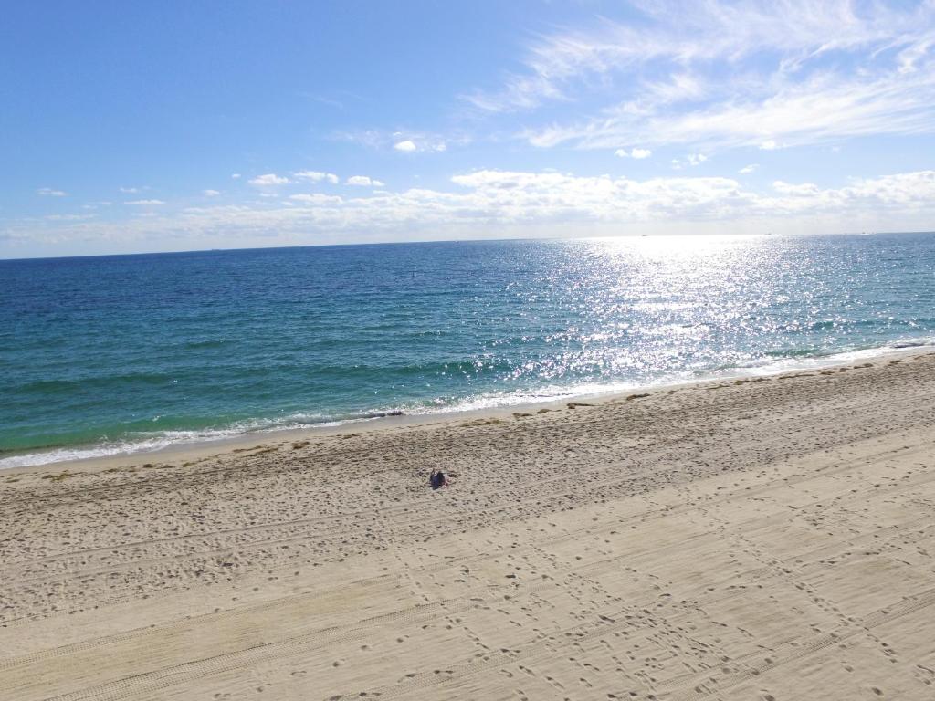 a person walking on a sandy beach near the ocean at Best Florida Resort in Fort Lauderdale