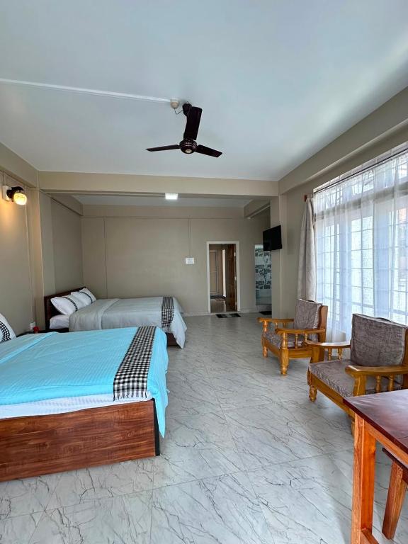 a bedroom with two beds and a ceiling fan at Tre Lum Homestay in Jowai
