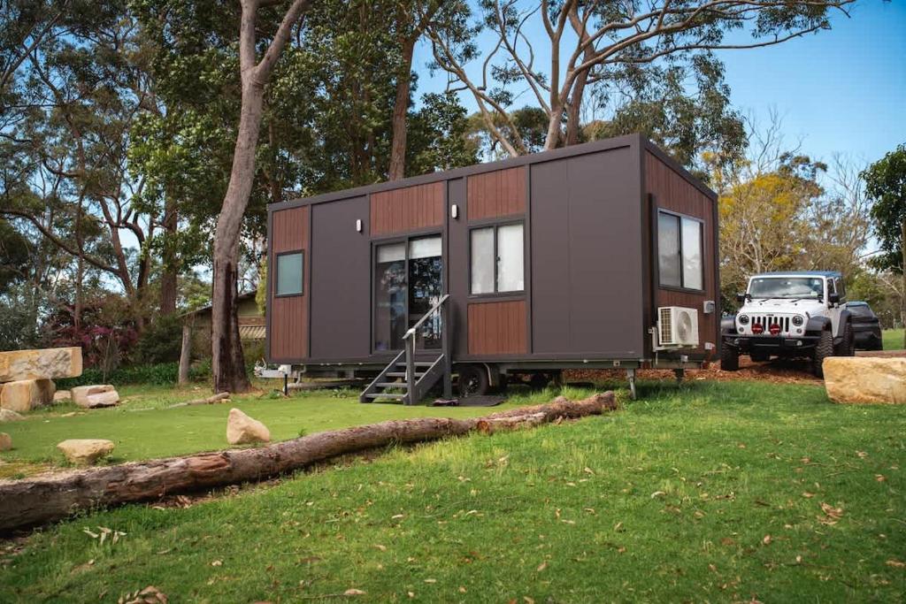 a tiny house sitting on top of a lush green field at The Lorikeet Tiny Home with Stunning Views in Canoelands