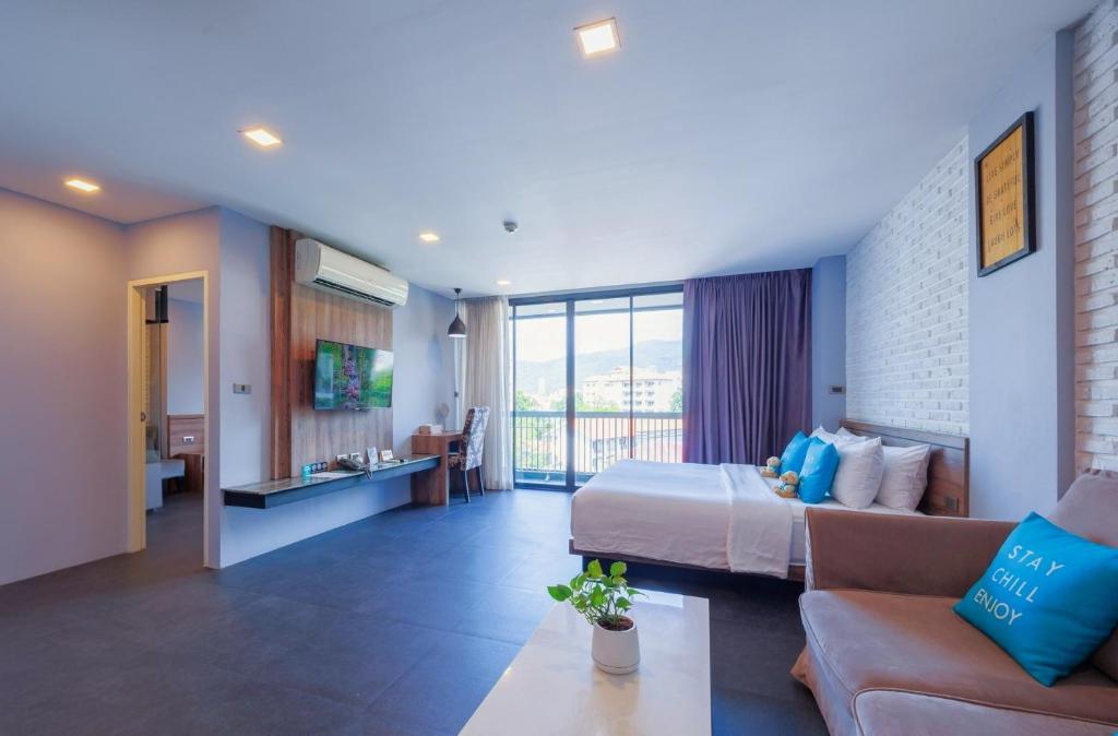 A spacious-looking room combines a bed, sofa, coffee table, desk and balcony-facing window.