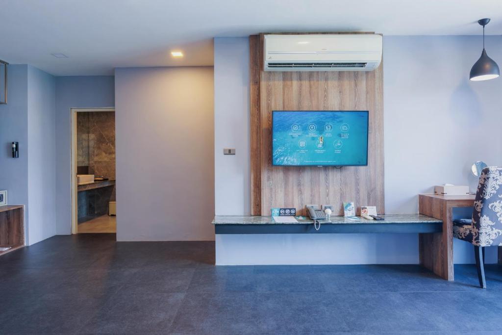 A hotel reception area presents a long service counter beneath a television and air conditioner.
