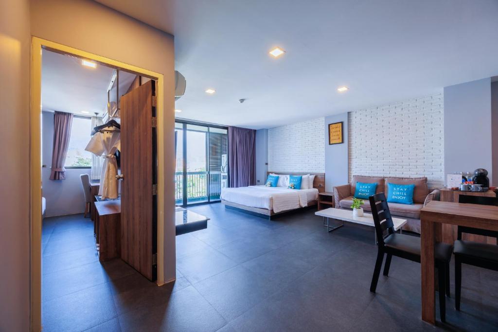 A spacious-looking suite combining a bed, sofa, dining desk and balcony doors.