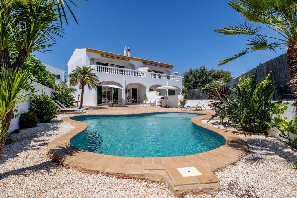 a villa with a swimming pool in front of a house at Luz Sun Poolhouse in Luz