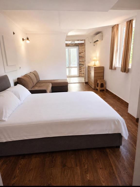 a bedroom with a large white bed and a couch at W beach house in Buljarica