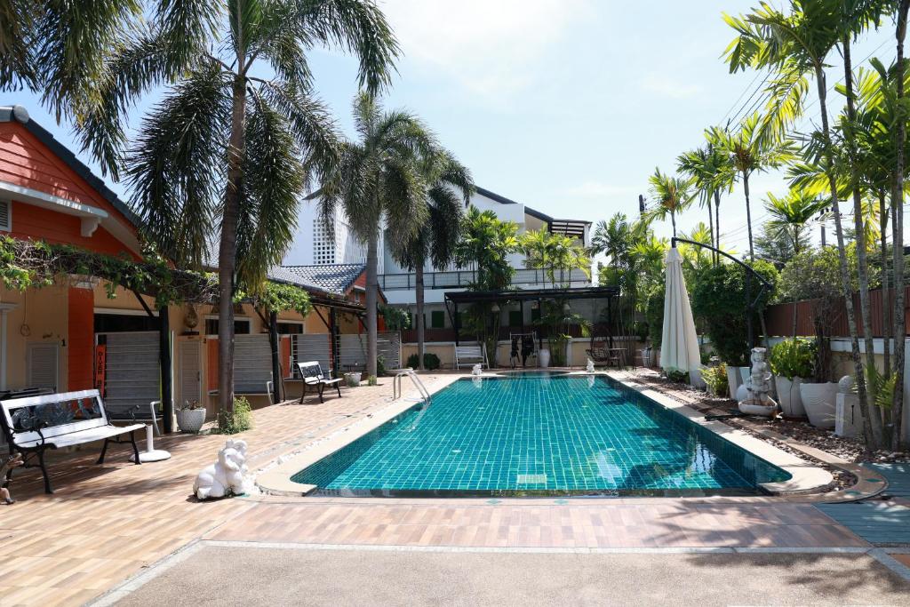a swimming pool with palm trees and a building at Chalong Pool Courtyard in Ban Na Bon