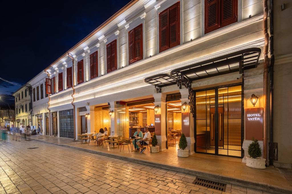 a street with people sitting outside of a building at Vatër Hotel in Shkodër