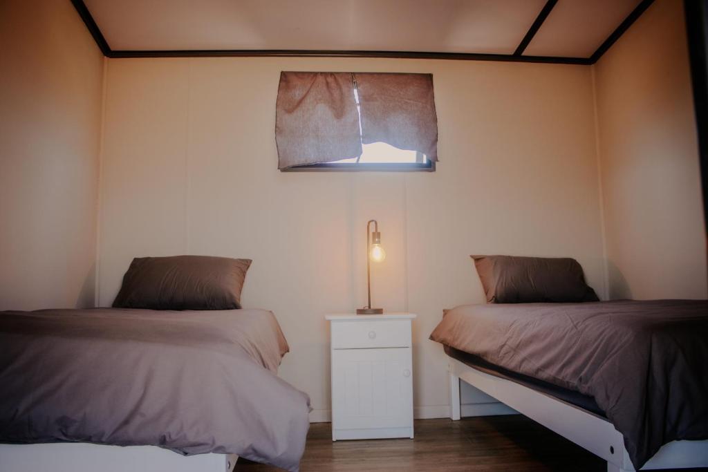 a room with two beds and a lamp and a window at Karoo 62 Bush Motel in Ladismith