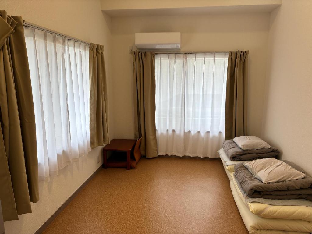 a room with two beds and a large window at apartment hotel myu in Mito