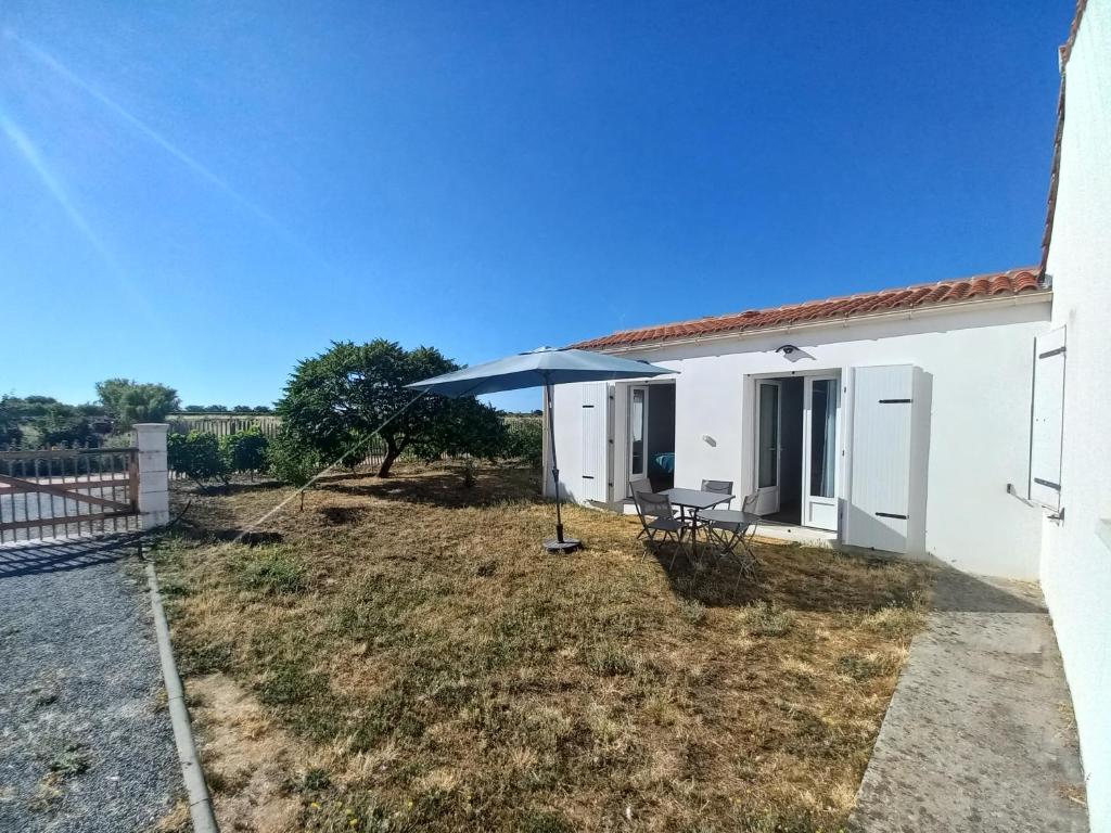 a white house with a table and an umbrella at Échappée iodée et nature à l'Île d'Oléron in Saint-Georges-dʼOléron