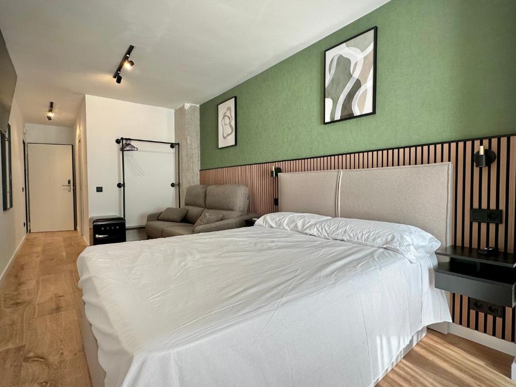 a bedroom with a white bed and a green wall at Akasa Rooms Estación in Alicante