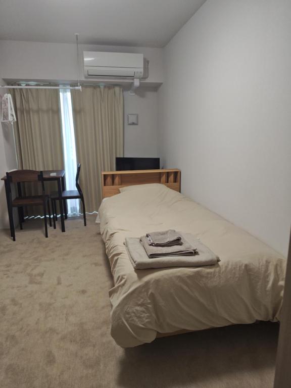 a bedroom with a bed and a table and a chair at StadtLeben東北ゲートウエイ2新築広々仙台駅徒歩5分 in Sendai