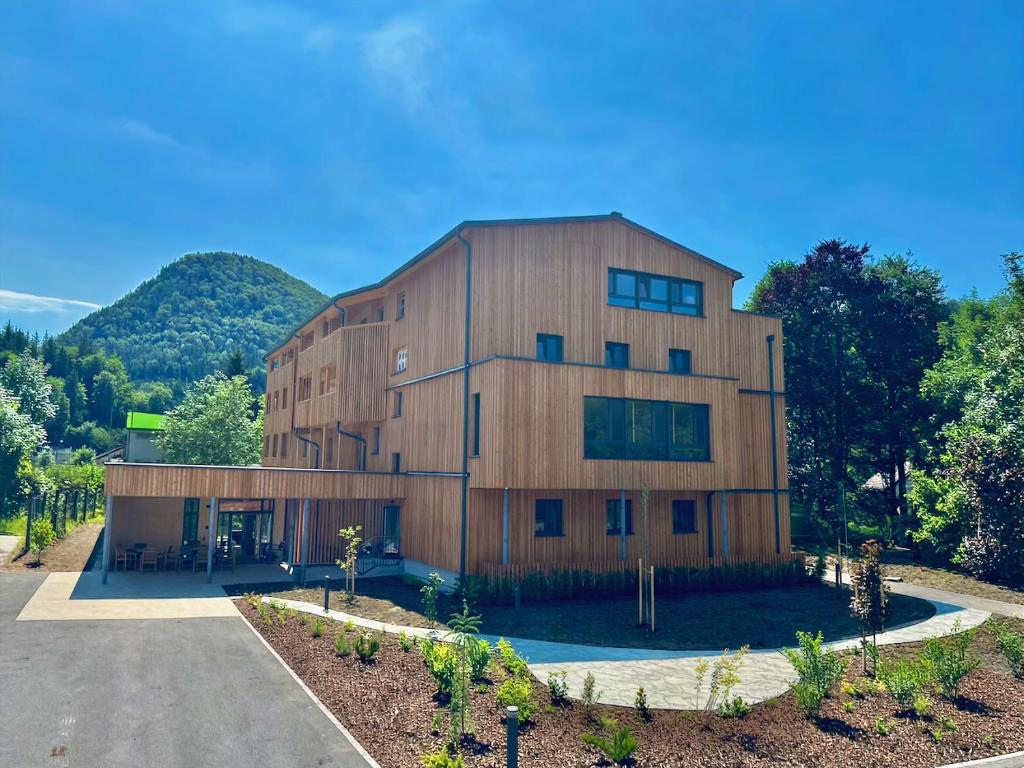 a large wooden building with mountains in the background at Haus der Achtsamkeit in Grünau im Almtal