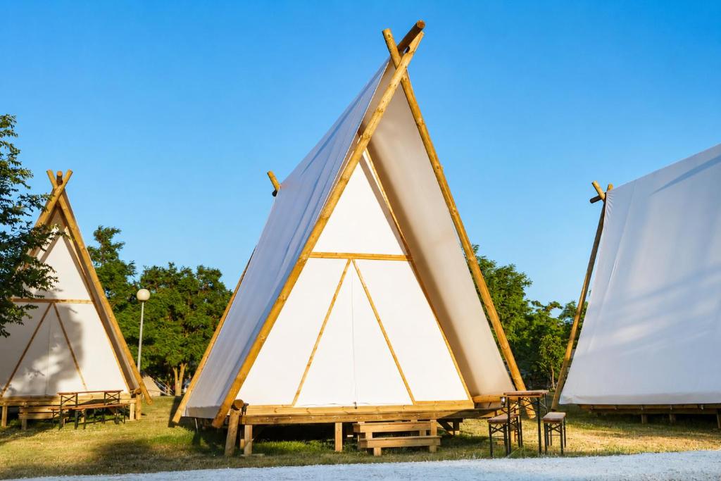 a group of three triangular tents sitting on the grass at Kampaoh Mendigorría in Mendigorría