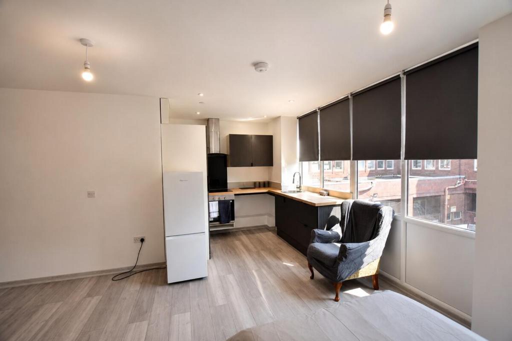 a living room with a chair and a kitchen at Stylish Flat in Peterborough Centre in Peterborough