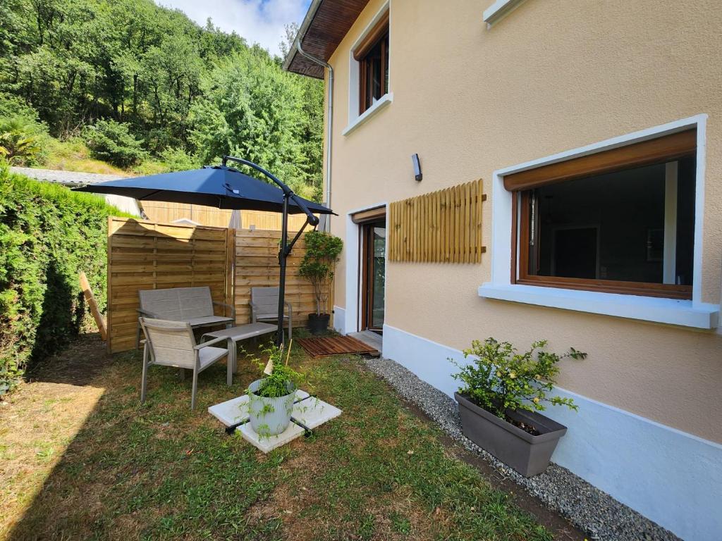 a patio with a table and an umbrella next to a house at la perle du pibeste in Agos-Vidalos