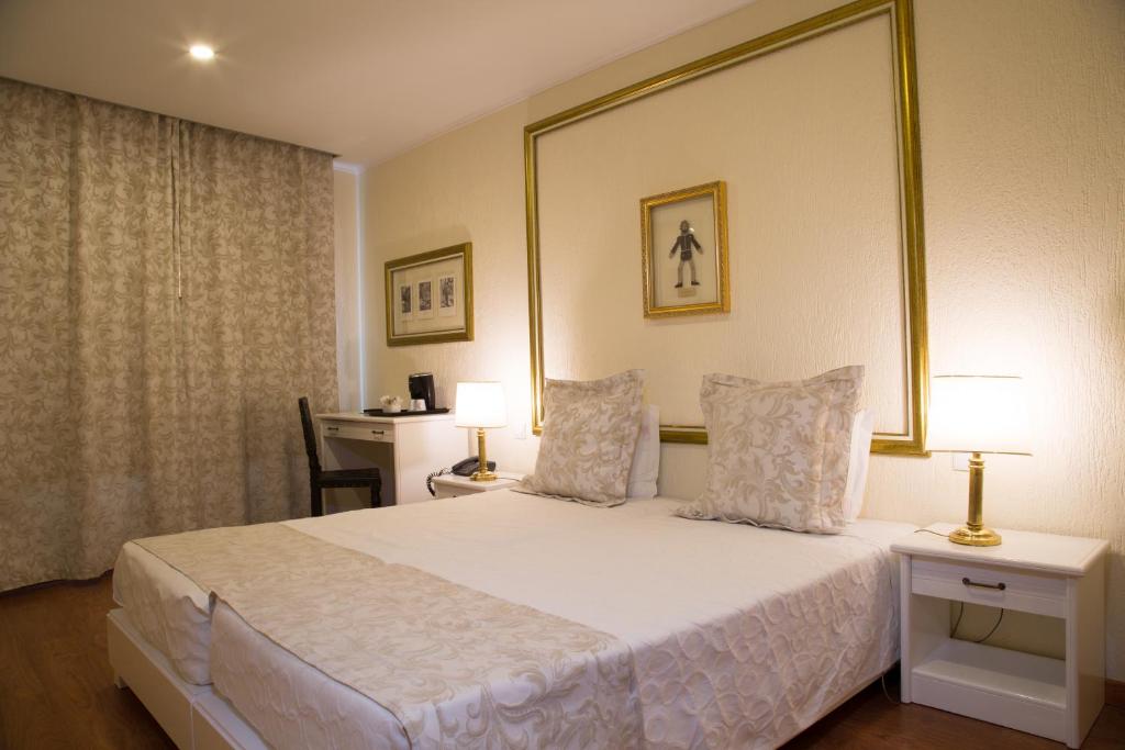A traditional bedroom with a double bed, bedside lamps and a separate desk against the back wall.