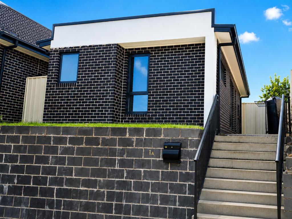 a house with a brick wall and stairs at Matildas Urban Escape 6-Min Station & Shops in Campbelltown South