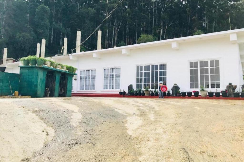 a person standing in front of a white building at Siriliya Homestay - Foreign Tourists Only in Nuwara Eliya