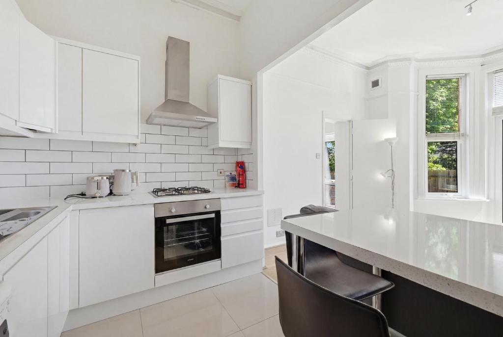 a white kitchen with white cabinets and a stove at Madeley Oak in Ealing