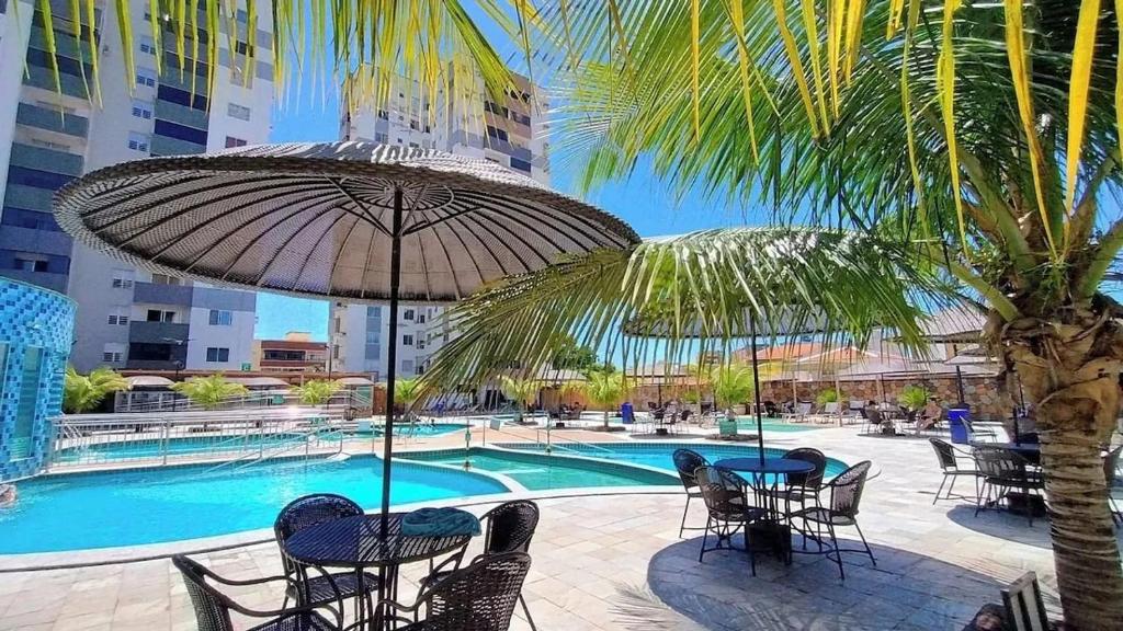 a pool with tables and chairs and a palm tree at CRCN - Aquarius Flat in Caldas Novas