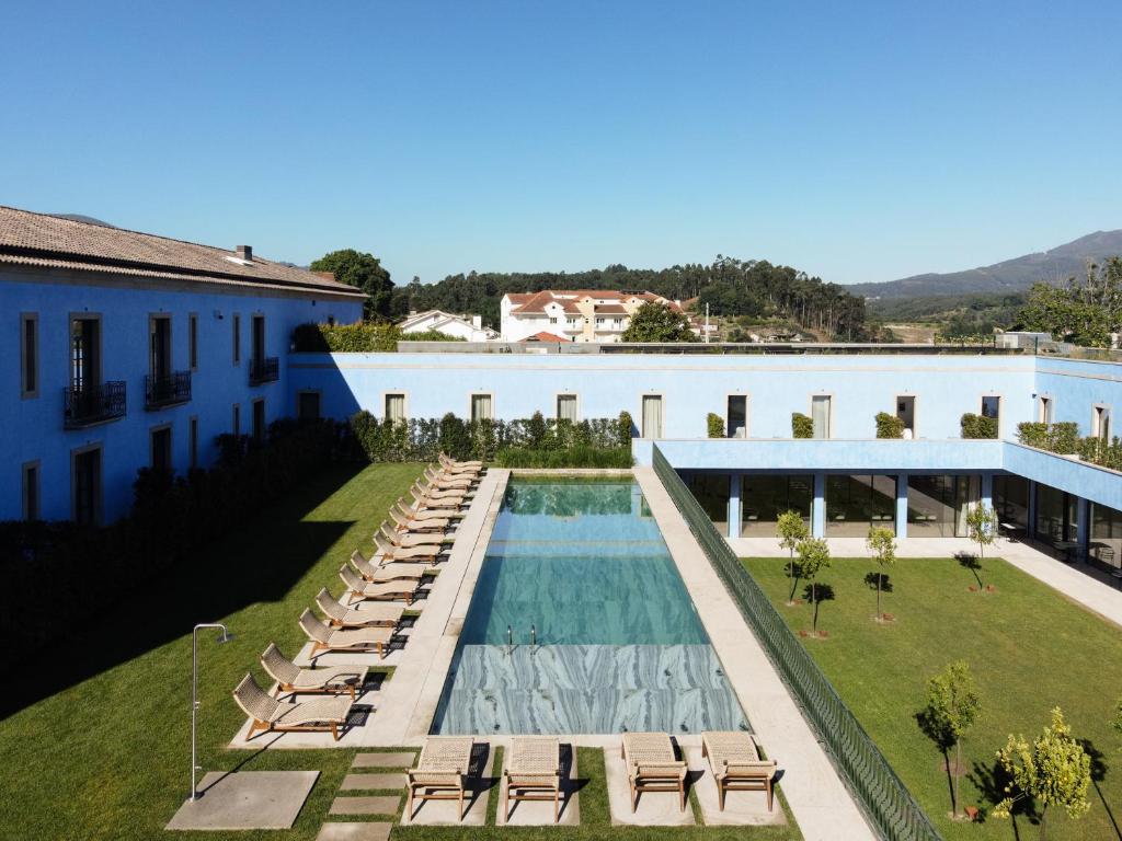 a swimming pool with lounge chairs and a building at Oca Grande Hotel Do Pezo in Melgaço