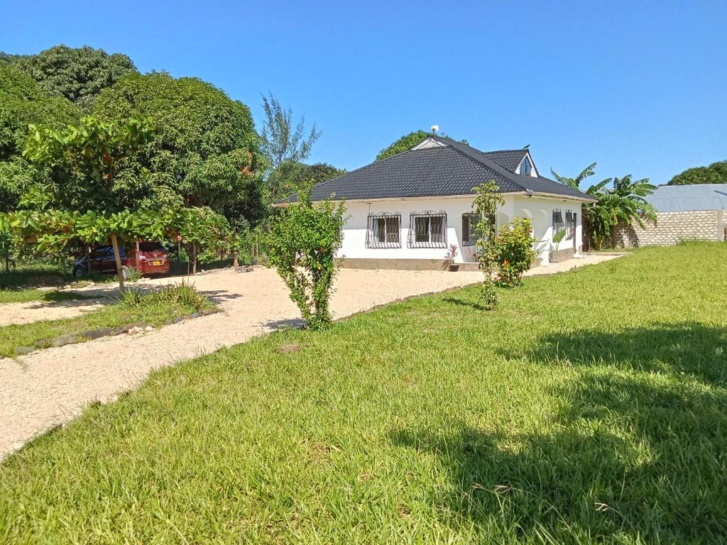 a white house with a grassy yard in front of it at Nyumba Nzuri in Ukunda, Diani in Ukunda