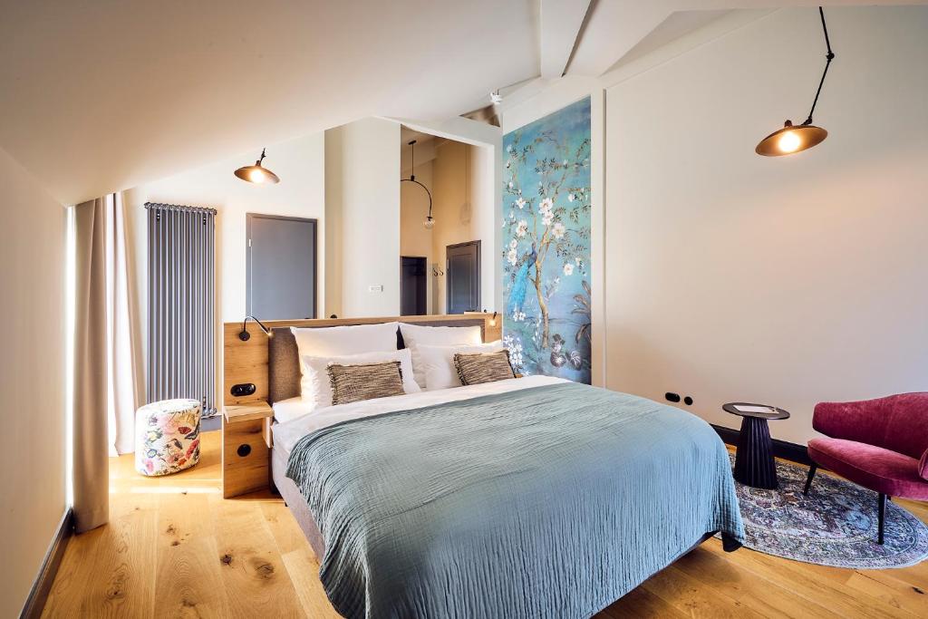 a bedroom with a large bed and a red chair at Hotel Lahneck in Nievern