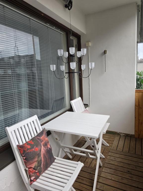 a white table and chairs on a porch with a chandelier at Linnankatu Apartment in Savonlinna