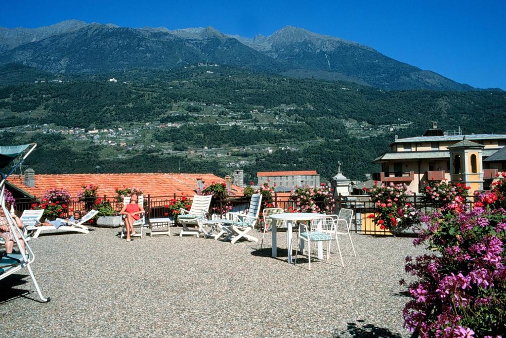 un gruppo di sedie e tavoli su un tetto con montagne di Hotel Margna a Morbegno