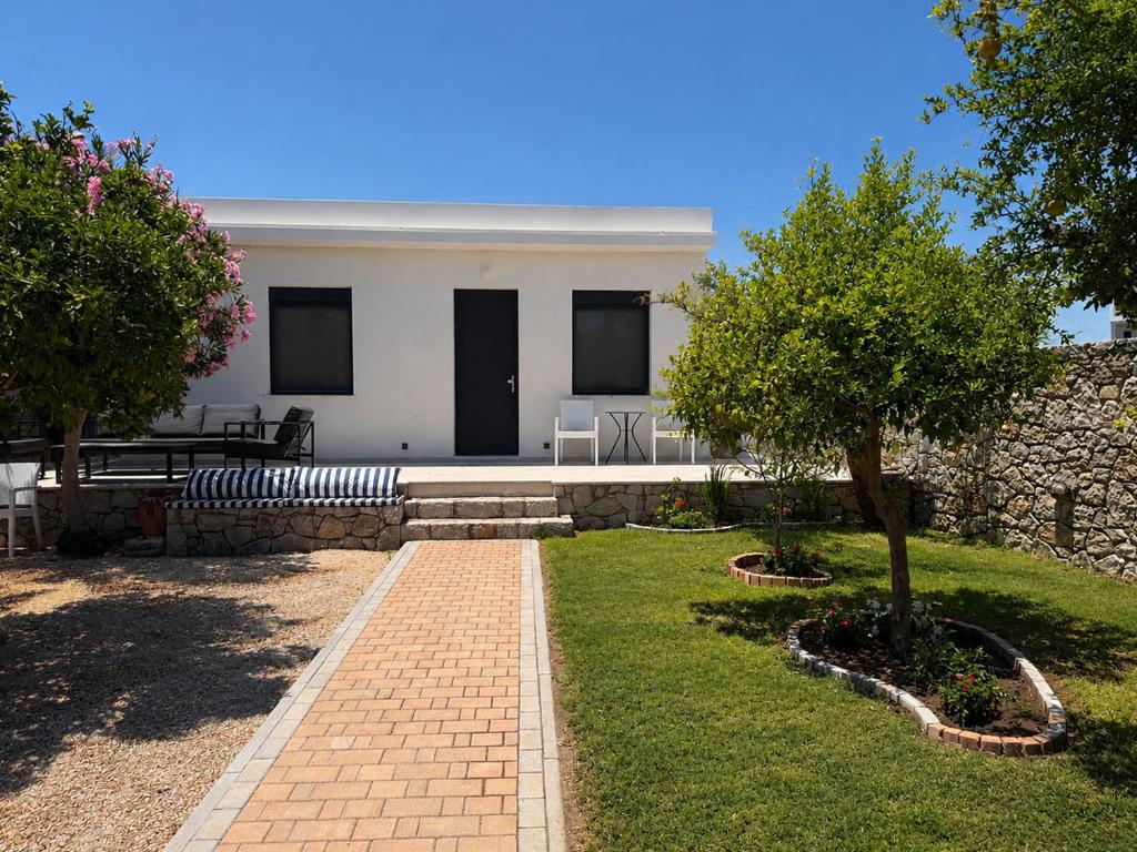 a white house with a brick pathway in front of it at ELÉNAS slow living villa in Faliraki