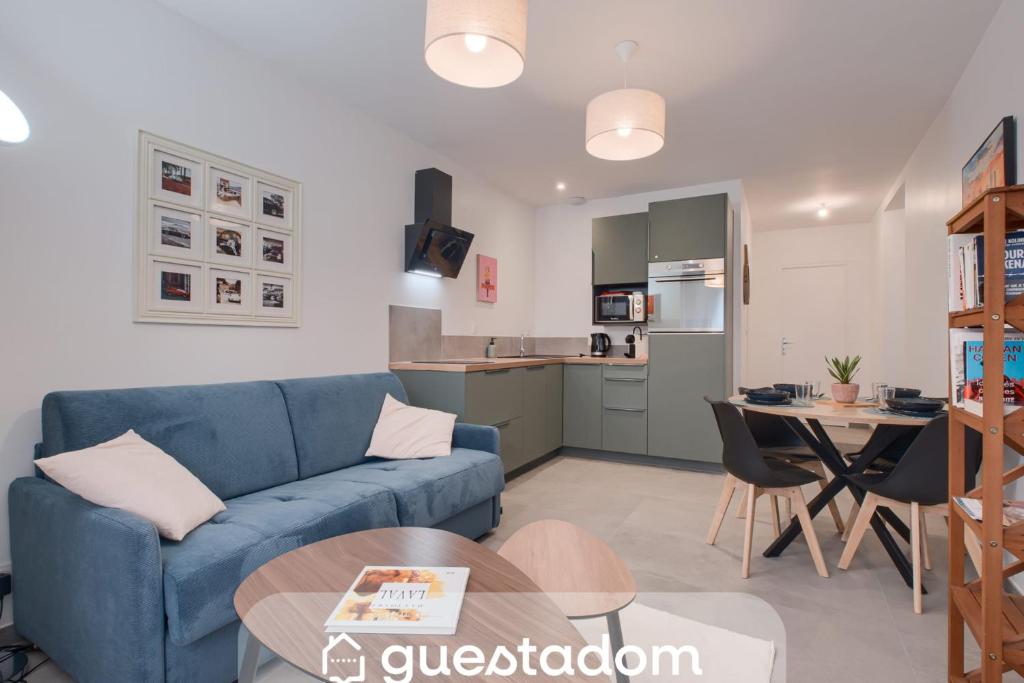 a living room with a blue couch and a kitchen at Le Cocon de Cossé - Wifi - 300m Centre in Cossé-le-Vivien