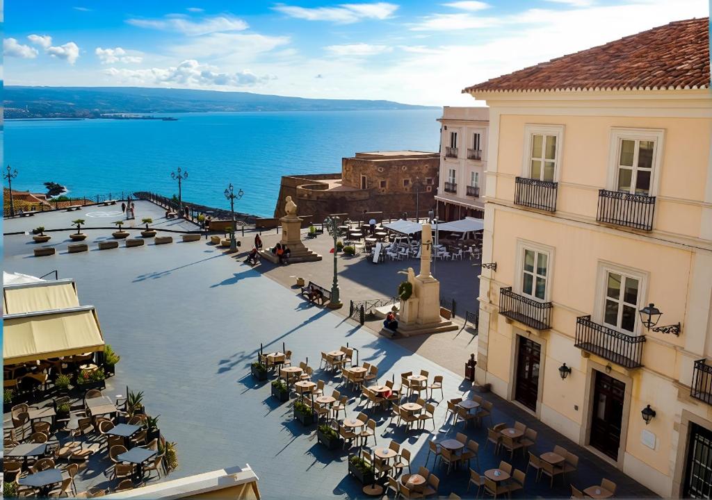 an empty plaza with tables and chairs in front of the ocean at Hotel della Piazza in Pizzo