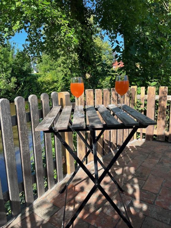 two wine glasses on a wooden table next to a fence at Huus Johann in Greetsiel