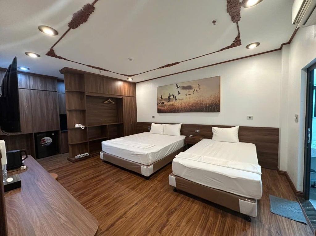 a bedroom with two beds and a desk and a tv at Khách Sạn Ka Long in Móng Cái