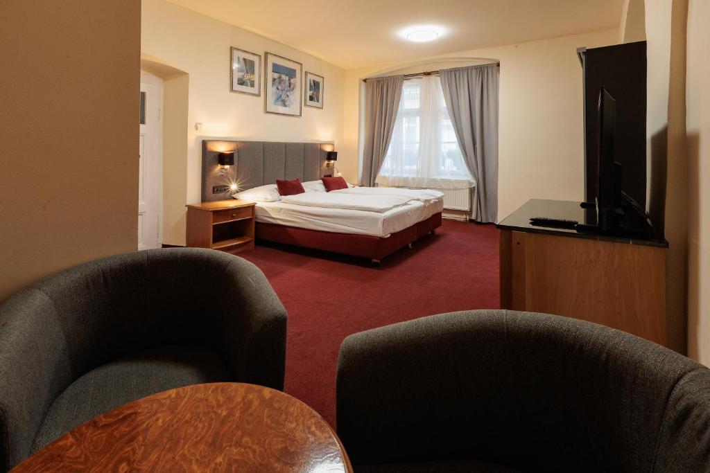 a hotel room with a bed and two chairs at Pension U Lilie in Prague