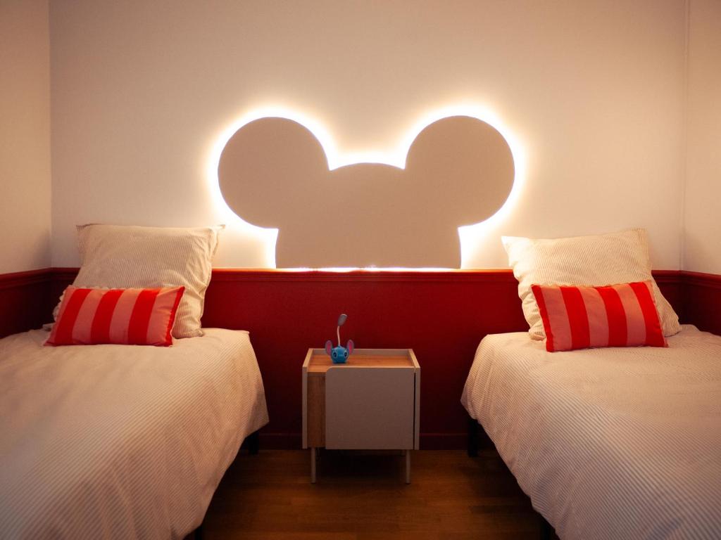 two beds in a room with a wall with an elephant light at Disneyland Magic Home in Couilly-Pont-aux-Dames
