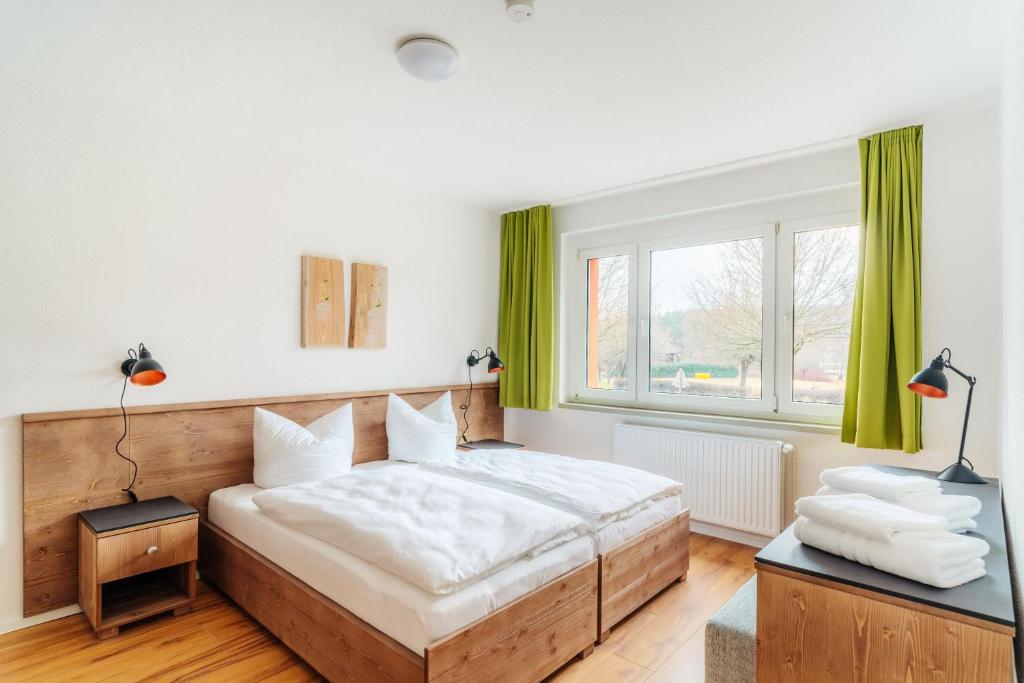 a bedroom with a large bed with green curtains at Bodeapartment 8 in Elend