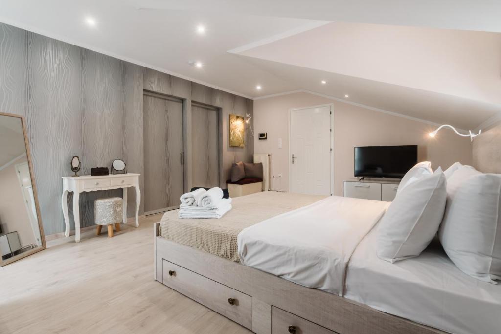 a bedroom with a large white bed and a television at Angelikis Maisonette in Kastoria
