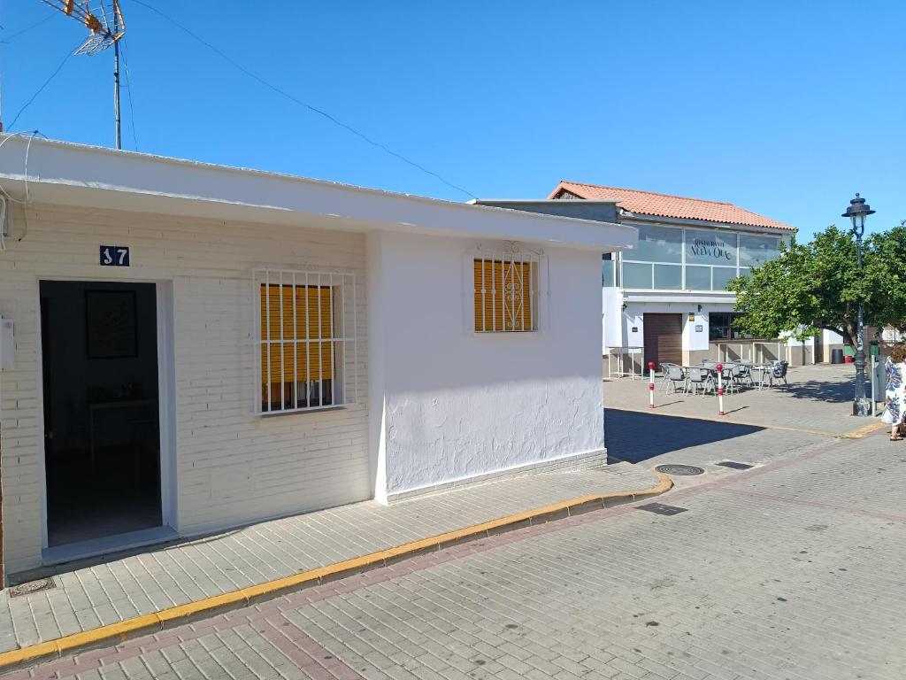 a white building with a door on a street at Marenga in El Rompido