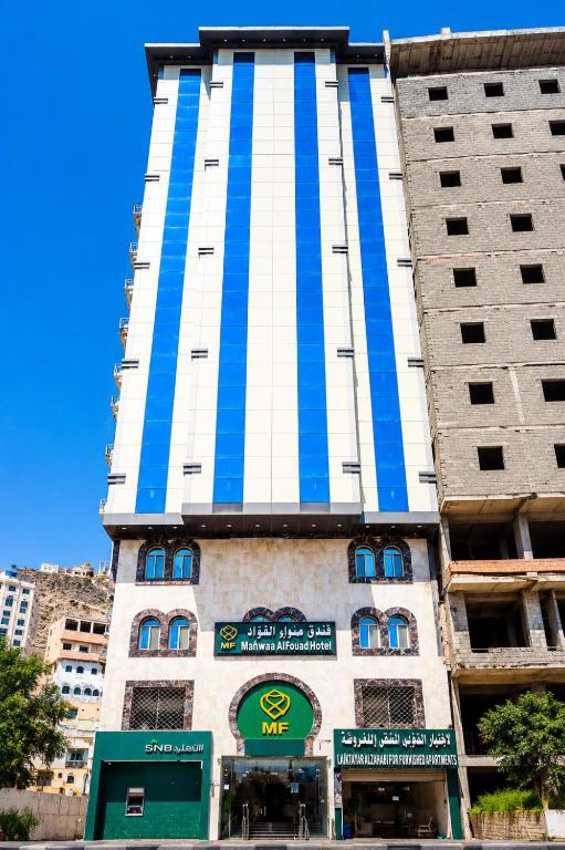 a tall building with blue and white stripes on it at فندق مهوى الفؤاد 1 ذاخر توصيل مجاني للحرم Mahwa Alfoad 1 Hotel free bus to Haram in Mecca