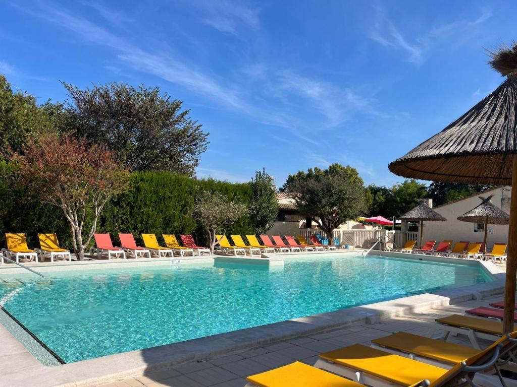 a large swimming pool with lounge chairs and umbrellas at Camping Pegomas in Saint-Rémy-de-Provence