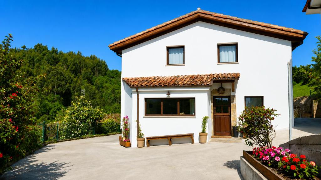 a white house with a bench in front at La Casina de San Pedro Ribadesella in Ribadesella